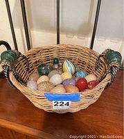 Wicker basket filled with assorted decorative eggs of glass and porcelain in multiple colors