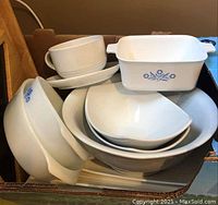 Stack of white CorningWare bowls and dishes with blue floral design showing variety of sizes