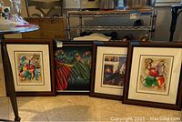 Four framed and matted wall art leaning against shelving