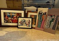 Five pieces of wall art including three framed and two canvassed artworks, arranged on floor and furniture.
