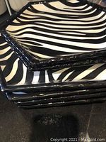 Stack of six hexagonal black and white zebra stripe patterned plates with black edges, showing glossy finish and geometric shape.