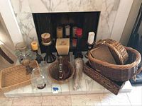 Lot arranged on a fireplace hearth with baskets stacked and candles arranged in front and on top