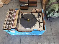 Top-down view of the record player with vinyl albums in a cardboard box