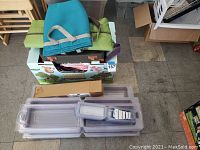 Photo showing fabric hand bags on top of a colorful box labeled Store More System, with plastic closet storage trays stacked below.