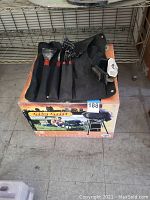 Black fabric roll-up case open with BBQツール including spatula, fork, tongs, and grill brush on box.