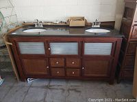 Front view of wood vanity with marble top, sinks, faucets and hardware on top