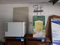 Photo showing the white mini refrigerator on the left and the beverage dispenser with acrylic container and metal stand on the right