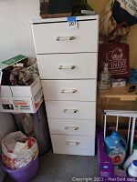 Front view of the white chest of drawers with handles and visible surface wear