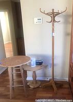 Wooden hall tree with hooks, two small wooden occasional tables, and other items on tables against wall