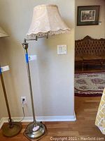 Full view of the floor lamp showing metal stand and fabric shade with decorative trim