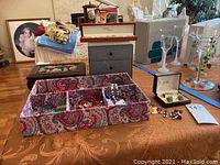 Wide view of table showing costume jewelry boxes, jewelry pieces including bead necklaces, cuff links, and bracelets spread out on a fabric organizer and table surface