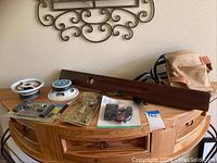 Leather tool belt, wooden vintage level, FM signal amplifier, tire repair kit, and other small items on a wooden dresser.