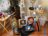 Overall view of lot with various home decor, framed artwork, travel bags, and candle holders on wooden trays and floor