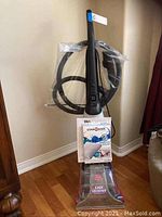 Full upright view of Dirt Devil Easy Steamer deep cleaner with hose attachment wrapped in plastic and manual attached on front.