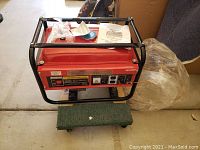 Front view of red generator showing fuel tank and paperwork on top