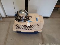 Dog crate in beige and dark blue plastic with ventilation holes, showing overall condition and size.