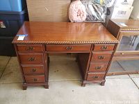 Front view showing center knee-hole, slim top drawer and three drawers on each pedestal with carved rope edge framing top