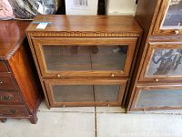 Front view of oak barrister's bookcase with two glass-fronted shelves and carved trim along the top edge.