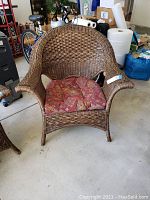 Front view of the wicker wing back chair with cushion, showing the woven wicker design and patterned seat cushion.