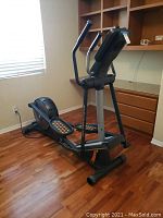 Full view of the elliptical machine showing frame, pedals, and console in a room setting