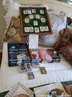 Framed baseball card display with cut-out vintage player images, various card boxes, and loose cards displayed on a bed.