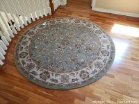 Full view of the round floral patterned rug on a wooden floor near staircase with a diameter of 72 inches.