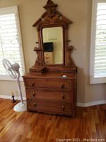 Full view of Victorian antique wooden dresser with swivel mirror in a room showing the entire piece with top section attached.