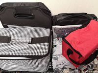 Photo showing several reusable bags including a large houndstooth patterned bag, black Case Logic bag, red insulated lunch bag, and a black expanding storage container.