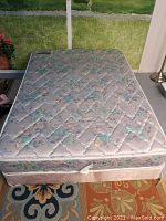 Full view of the double mattress on top of the box spring showing floral quilted surface and thickness.