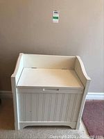 Front view of white painted wooden hall bench showing bead board detail and hinge on top for storage access