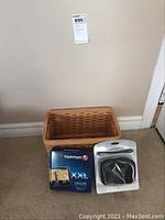 Photo showing the wicker basket, TomTom XXL 540L GPS box, and black carry case in packaging together on floor.
