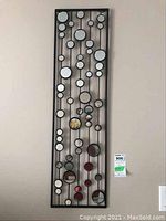 Close up of one of the two rectangular wall art panels with multiple circular mirrors and vertical black metal lines.