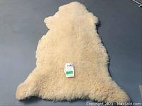 Top-down view of full sheep skin mat showing natural sheep shape and curly wool texture.