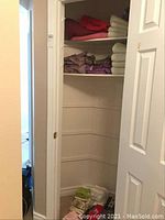 Closet image showing shelves with folded towels and quilt covers in various colors including red, maroon, cream, and purple.
