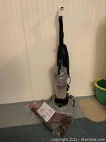 Front view of Bissell Aeroswift Turbo vacuum with hose and user manual on the floor.