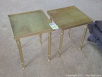 Pair of small square gold-tone occasional tables with raised filigree edges and stone-look tops, legs have decorative banding.