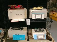 Overview of four model cars on shelving with boxes and COAs