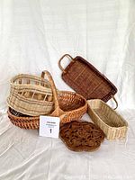Overview of all five wicker baskets and the wood trivet arranged on a white backdrop.