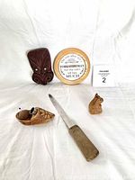 Image showing all five items: carved wooden head with mother of pearl eyes, carved wooden shoe pin cushion, small carved wooden thimble holder figure, metal knife, wooden lid with Yorkshire-themed text.