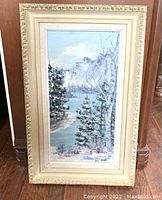 Full view of the framed acrylic painting showing the winter lake and mountain landscape, including the ornate cream and gold frame and matting.
