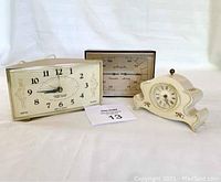 Three vintage timepieces including a rectangular dial clock, a decorative footed clock, and an Airguide gauge