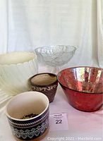 Five assorted pots and bowls arranged on white cloth background, showing different sizes, colors, and textures.
