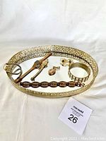 Overview photo of the oval mirrored jewelry tray containing all jewelry items including watches, cuff links, brooch, pendant, and bracelet.