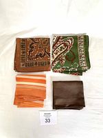 Four vintage neck scarves laid flat showing different patterns and colors including brown intricate design, green paisley, orange stripes, and solid brown.