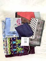 Photo showing six folded scarves stacked on top of each other with various colors and patterns visible.