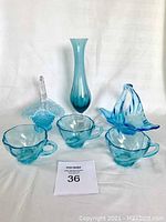 Full lot showing all six turquoise glass items including vase, teacups, and baskets on white background