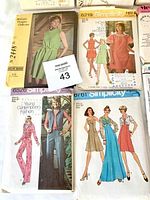 Photo of various sewing pattern envelopes showing vintage women's dresses, jumpsuits, and casual wear from McCall's and Simplicity with illustrations and model photos.