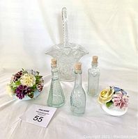 Photo showing porcelain floral figurines, cornflower glass basket, and collectible glass bottles arranged on white background