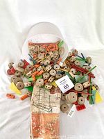 Full view of Tinker Toy wooden pieces spilled from white container alongside a set of original instruction sheets.