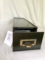 Front view of the steel drawer showing brass handle and label slot.